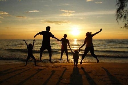 A family jumping in front of a beach